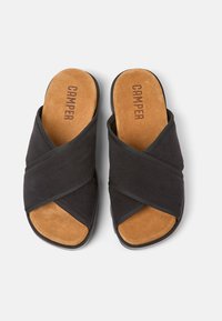 Sandali con fascia incrociata neri, in suede, con soletta imbottita color cuoio e suola in gomma testurizzata. Il marchio "Camper" è visibile.