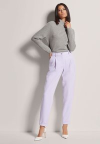 Gray ribbed sweater and light purple pleated trousers, featuring tapered legs, a button detail, and white pointed-toe heels.