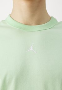 Lys grøn bomulds t-shirt med rund hals og et hvidt Jumpman-logo trykt på brystet. Blød tekstur, afslappet design.