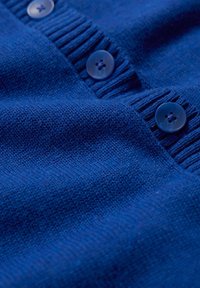 Button-up cardigan in deep blue knit fabric, featuring ribbed accents and two round plastic buttons with a subtle sheen.