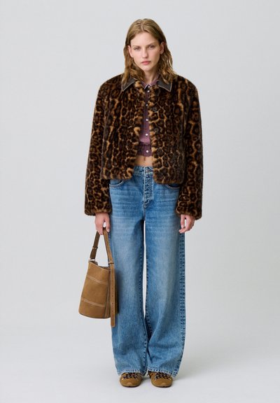 Giacca in pelliccia ecological con stampa leopardata, dal taglio corto, abbinata a jeans blu a gamba larga a vita alta e una borsa a secchiello in suede marrone.