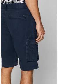 Shorts cargo bleu marine en coton avec une finition texturée. Comprend des poches latérales, un ourlet cousu et un design décontracté.