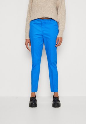 Lyseblå slim-fit bukser med en glat tekstur, bæltestropper og sidelommer, parret med sorte sko og en lys beige sweater.