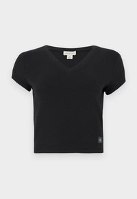 Black short-sleeve V-neck t-shirt made of ribbed fabric. Features a small, branded tag on the bottom left. Simple, fitted design.