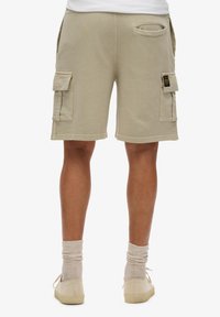 Beige cargoshorts met twee zijzakken, zachte textuur en een losse fit, met een achterzak en zichtbare stiksels.