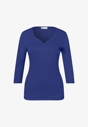 Dopasowana niebieska damska bluzka z długim rękawem, zaokrąglonym dekoltem w kształcie litery V, bez wzorów i ozdób.