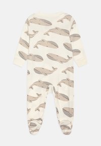 Cremefarbener Overall mit einem sich wiederholenden Wal-Muster in sanften Beige- und Grautönen. Verfügt über lange Ärmel und elastische Bündchen.