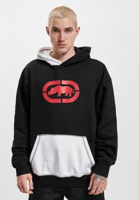 Zwarte hoodie met een rood neushoornlogo en een witte kangoeroezak. Heeft een dubbele capuchon met een grijze voering.