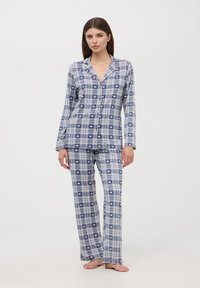 Pigiami a quadri blu e bianchi con accenti rosa a forma di cuore, composti da una camicia con bottoni e pantaloni lunghi, realizzati in un tessuto leggero.