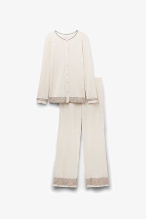 Completo pigiama da donna in beige chiaro, composto da una blusa con bottoni e maniche lunghe, rifinita in pizzo, abbinata a pantaloni con dettagli in pizzo.