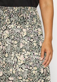 Saia com estampa floral apresentando uma base preta com flores em tons pasteis, uma cintura elástica e um design fluido para conforto e liberdade de movimento.