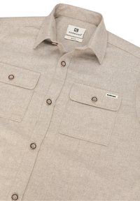 Camicia button-up beige realizzata in tessuto testurizzato con due tasche sul petto, bottoni marroni e un'etichetta del marchio cucita sulla tasca sinistra.