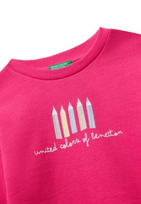 Felpa rosa con cinque disegni di matite multicolori e il testo "united colors of benetton" in bianco. Collo a girocollo ribattuto e texture del tessuto.