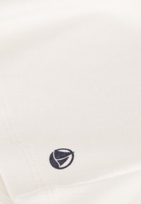 Crème stof met een gladde textuur, met een zwart logo nabij de rand. Eenvoudig ontwerp met strakke lijnen en minimale stiksels.