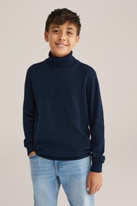 Mornarska pulover s turtleneck ovratnikom, izdelan iz mehkega blaga, z rebrastimi manšetami in ovratnikom, v kombinaciji s svetlo modrimi kavbojkami. Gladek, sproščen dizajn.