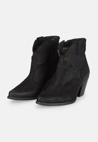 Botas de tobillo de ante negro con punta afilada, costuras decorativas y un tacón de bloque de altura media. Cuenta con un cierre de cremallera lateral y forro a rayas.