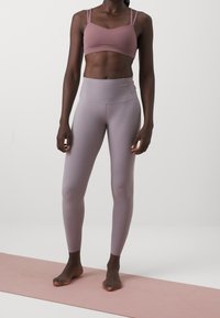 Top sportivo di un tenue color malva con spalline sottili abbinato a leggings malva a vita alta. Tessuto liscio e elastico con un fit slanciato, senza motivi visibili.