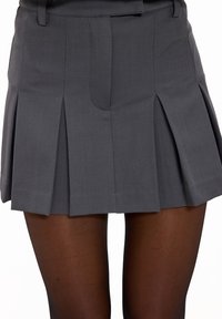 Jupe plissée grise en tissu à texture lisse. Dotée d'une ceinture et de multiples plis nets pour un design structuré.