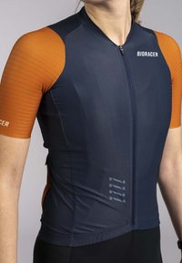 Maillot de cyclisme à manches courtes en bleu foncé et orange. Présente une coupe ajustée, une fermeture éclair à l'avant, des manches texturées orange et un branding subtil.