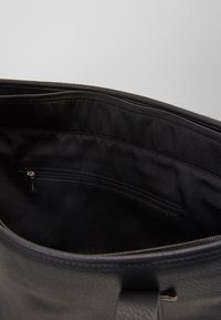 Borsa in pelle nera con texture liscia, dotata di una tasca interna con zip e un rivestimento semplice. La parte superiore ha un'apertura arrotondata.