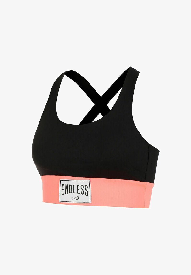 Sujeción deportiva negra con tirantes cruzados y banda elástica ancha color coral que presenta una etiqueta "ENDLESS" en el centro frontal.