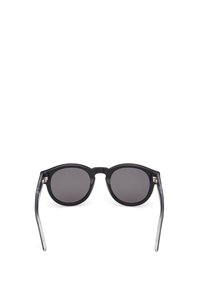 Gafas de sol de montura redonda con frente de plástico negro y brazos translúcidos en gris. Lentes oscuros con un acabado suave y sin patrones visibles o detalles de hardware.