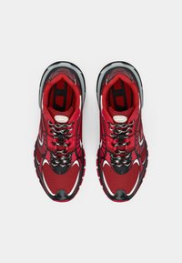 Pair of red and black athletic sneakers with white accents and patterned laces, viewed from above on a white background.