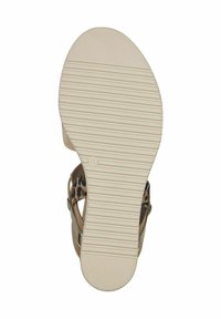 Calzature con una suola in gomma beige dotata di una texture antiscivolo, che presenta un design a stampa leopardata e una fascia tan con accenti metallici.
