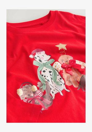 Červené tričko s ilustráciou psov v dovolenkovom oblečení. Obsahuje dalmatína, hnedého psa s čiapkou a tretieho psa s anjelskými krídelkami a mašľami.