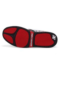 Shoe sole with a black and red color scheme, featuring a herringbone pattern, textured surface, and a branded logo panel.