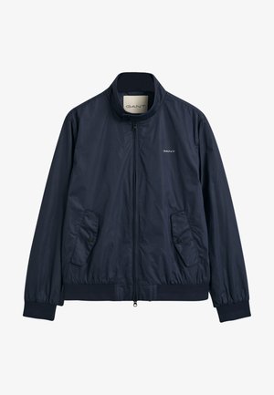Veste bomber en nylon bleu marine avec un col haut, une fermeture éclair à l'avant et deux poches latérales. Caractéristiques : poignets et ourlet élastiques, avec un logo discret.