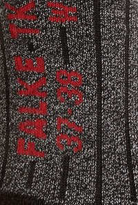 Chaussettes en tricot grises avec du texte et des motifs rouges, présentant une texture côtelée et des marquages de taille : "FALKE" et "37–38."