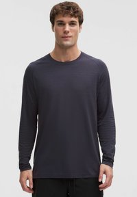 Ciemnoszara koszula z długim rękawem wykonana z teksturowanej tkaniny, z okrągłym dekoltem i rękawami raglanowymi, z delikatnymi poziomymi paskami.