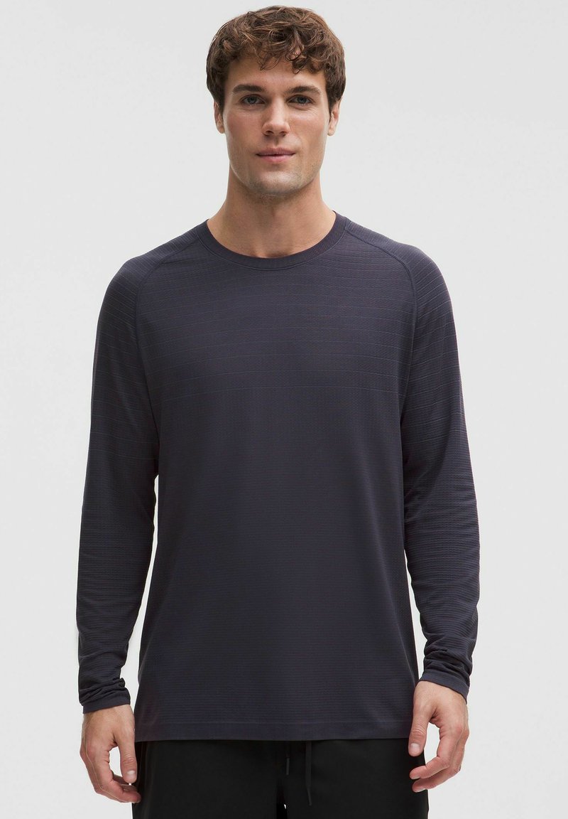 Ciemnoszara koszula z długim rękawem wykonana z teksturowanej tkaniny, z okrągłym dekoltem i rękawami raglanowymi, z delikatnymi poziomymi paskami.