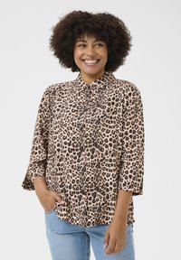 Blusa con stampa animale in beige chiaro e nero. Caratterizzata da una chiusura con bottoni frontale, colletto e ampie maniche a 3/4. Tessuto morbido e strutturato.