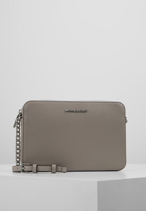 Sac bandoulière rectangulaire taupe Michael Kors avec fermeture éclair sur le dessus, chaîne argentée et section en cuir ajustable sur une surface blanche.