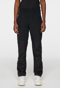 Svarta utomhusbyxor med en blandning av släta och texturerade material, flera zip-fickor och en tapered passform. Accentuerade med ett bälte.