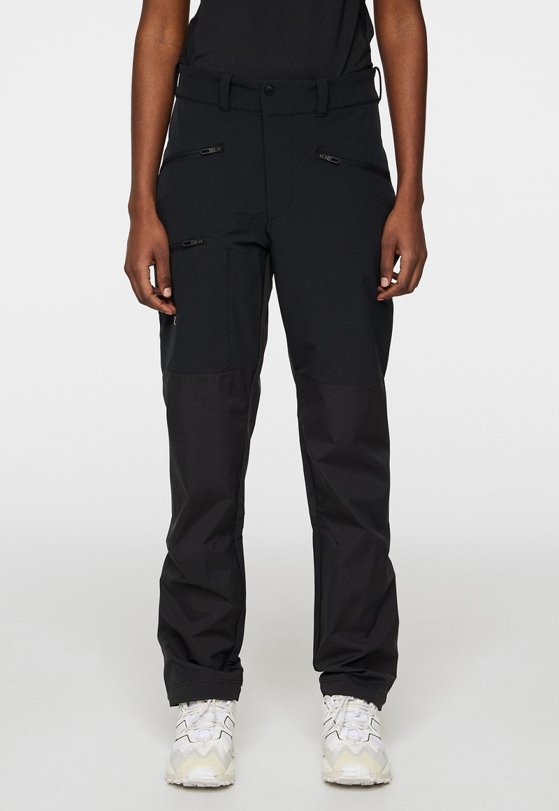 Svarta utomhusbyxor med en blandning av släta och texturerade material, flera zip-fickor och en tapered passform. Accentuerade med ett bälte.