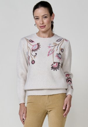 Lichtbeige gebreide trui met bloemenborduursel in roze, paars en bruin. Ribbelmanchetten en onderrand voegen textuur toe aan het ontwerp.