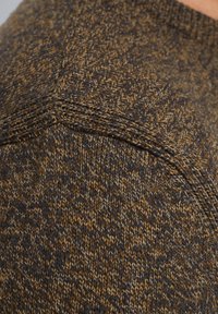 Pull en tricot texturé marron et beige présentant un motif en chevrons, un col côtelé et une coupe ajustée au niveau des coutures d'épaule.