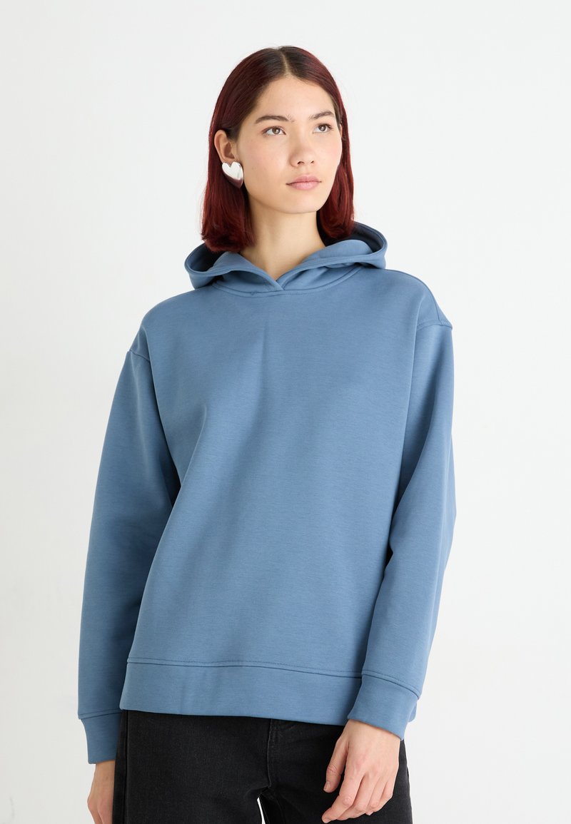 Světle modrá mikina s klokaní kapsou, design na přetahování a žebrované manžety. Měkká textura, se kapucí a dvojitým prošíváním.