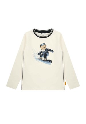 Chemise blanche à manches longues avec bordure noire et une représentation graphique d’un ours en snowboard portant des lunettes de protection et des vêtements d’hiver sur le devant.