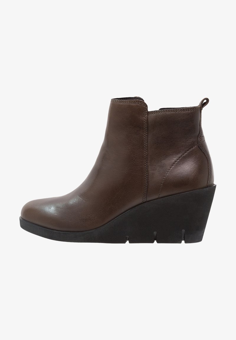 Botte de cheville en cuir marron avec un talon compensé, présentant une texture lisse, des détails de couture sur les côtés et une languette à l'arrière.