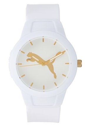 Montre-bracelet blanche avec un logo Puma doré sur le cadran, des index dorés et des aiguilles des heures, des minutes et des secondes dorées.