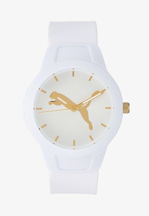 Montre-bracelet blanche avec un logo Puma doré sur le cadran, des index dorés et des aiguilles des heures, des minutes et des secondes dorées.