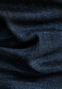 Tejido de denim azul oscuro con un ligero brillo, que muestra una textura suave y sutiles variaciones de color, destacando su patrón tejido.