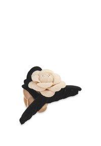 Sammets håraccessoar med en blek beige blomma och svarta blad, med en texturerad yta och lager av blad för extra dimension.