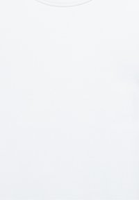 Kvinde med mørkt hår og briller holder en brun hund tæt ind til brystet og smiler blidt mod en ensfarvet baggrund.