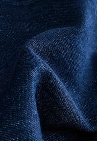 Tissu bleu marine avec un tissage texturé, affichant de légères paillettes lumineuses. Surface douce et légèrement réfléchissante avec des plis subtils.