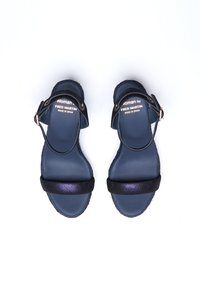 Marineblaue Sandalen mit einem strukturierten Riemen, glitzernden Akzenten, einem Knöchelriemen mit metallicschnalle und flacher Sohle. Das Etikett trägt die Aufschrift "Woman by Fred Martin."
